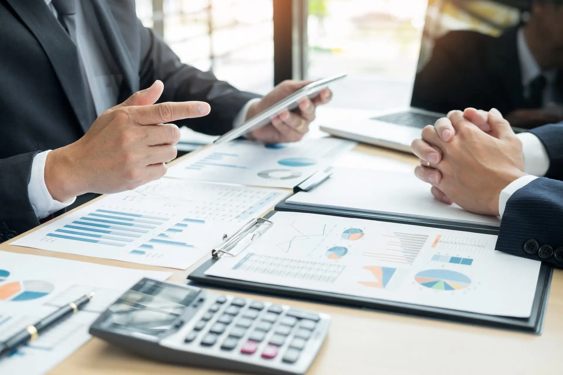 Business people talking discussing with coworker planning analyzing financial document data charts e1616122049107