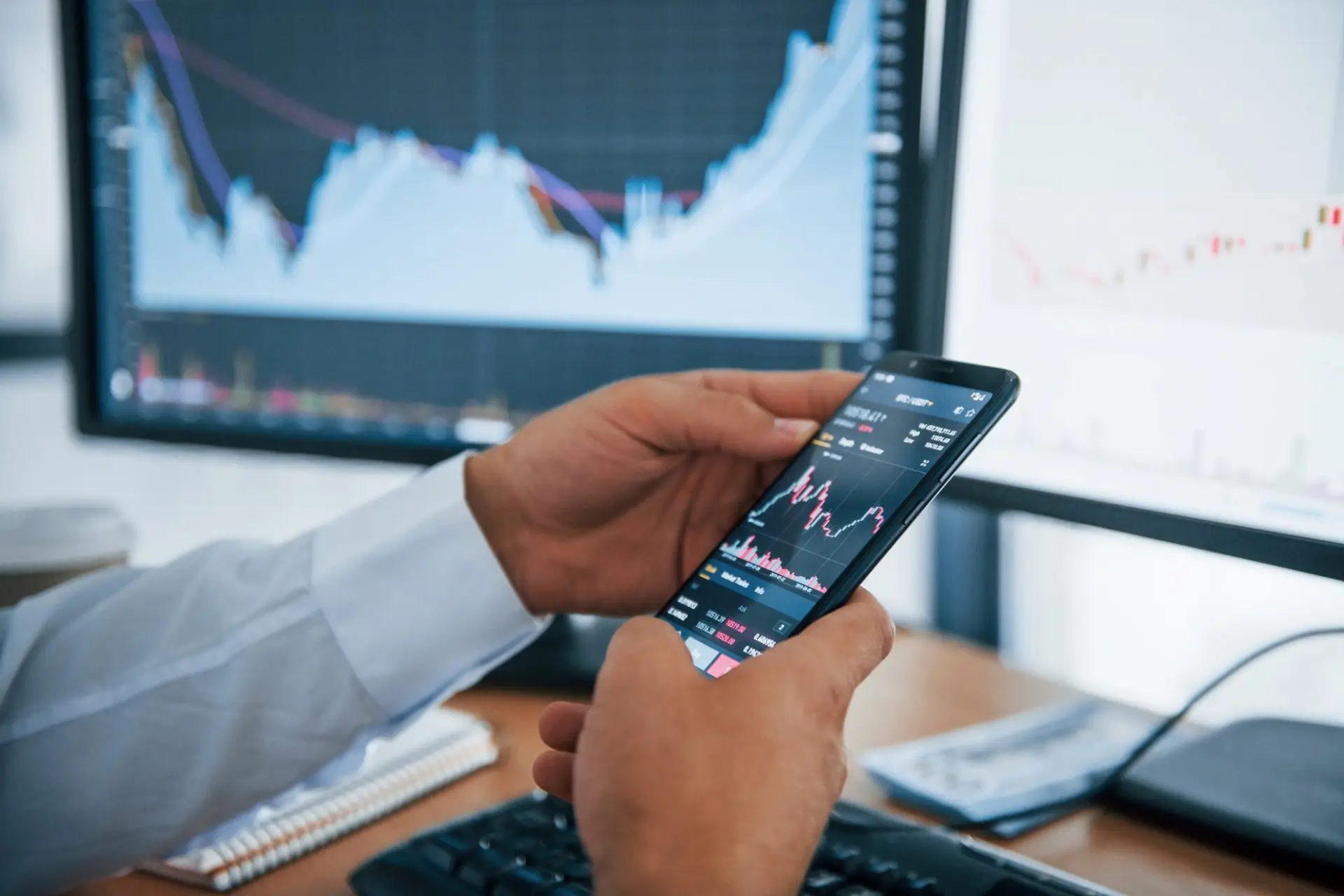 Businessman is in office with multiple screens conception of exchange and money e1616121974134