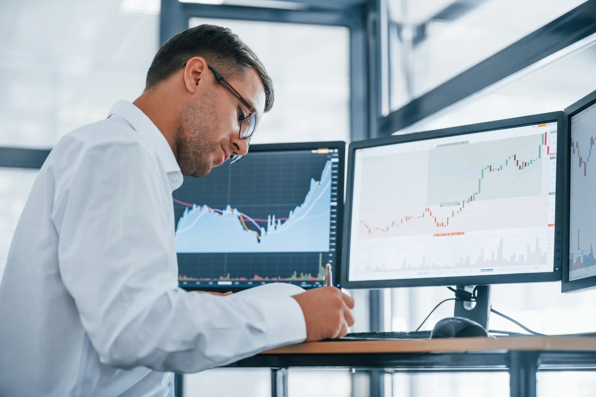 Young businessman in formal clothes is in office with multiple screens 2 e1616122034573
